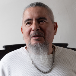 Bernito, an older Puerto Rican man with a long beard and a white shirt. 