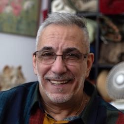 An older white man looking at the camera and smiling. 