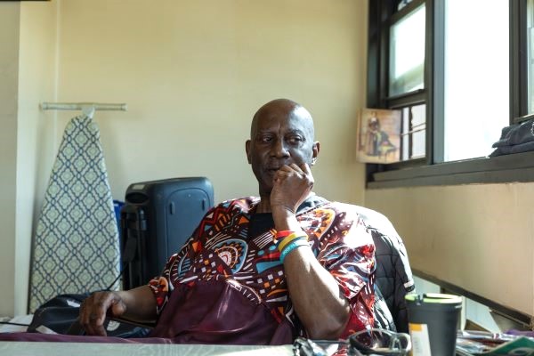 Billy, an older African American, sitting at table and looking off to the side.