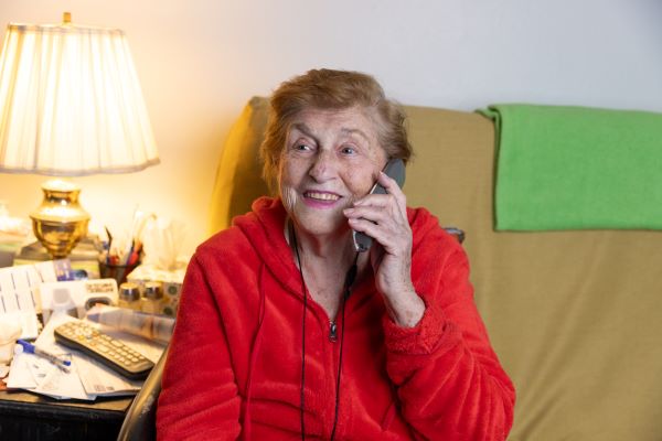 An older woman, Dorothy, sits on the couch, holding a phone to her ear.