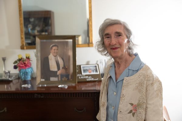Elaine stands in front of her fireplace mantel, which is full of family photos.