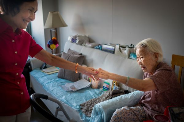 Po-Ling links hands with an older Asian American meal recipient.