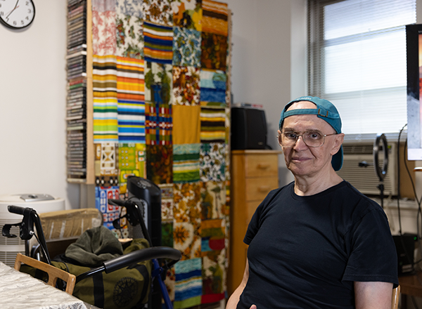 Rubem, a senior Citymeals on Wheels recipient in NYC, wears glasses and blue baseball cap.