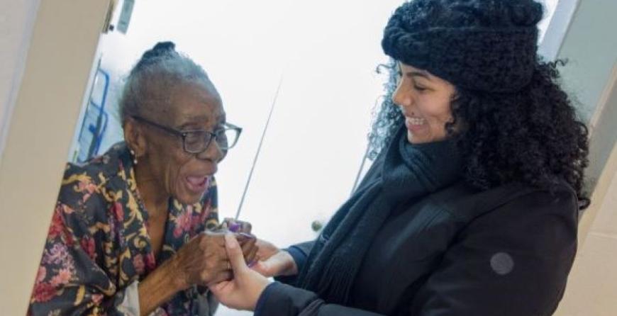 A volunteer holding hands with a smiling meal recipient. 