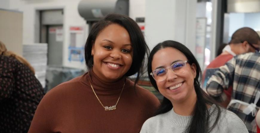 Two GoldenTree employees packing meals at a meal center. 