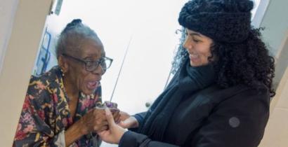 A volunteer holding hands with a smiling meal recipient. 